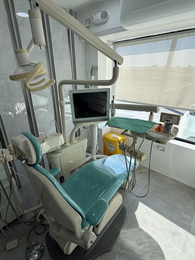 Detalle de un sillón dental con lámpara, bandeja de instrumental y monitor en un box de Clínica Pucalán